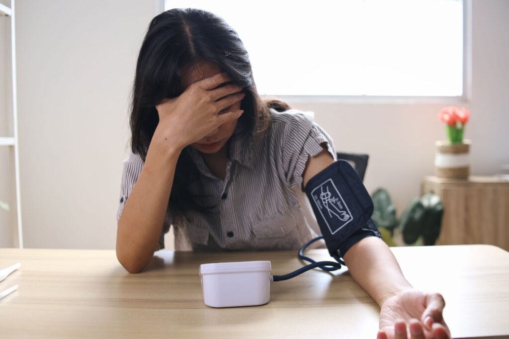 Woman checking blood pressure, looking anxious and stressed.