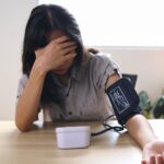 Woman checking blood pressure, looking anxious and stressed.