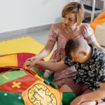 Caregiver helping autistic child with sensory learning activity